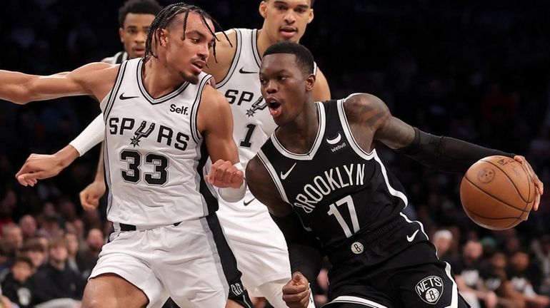 Nets guard Dennis Schroder drives to the basket against Spurs guard Tre...