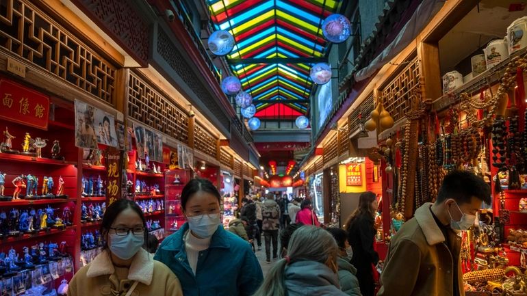 Visitors look at shops selling trinkets and souvenirs along a...