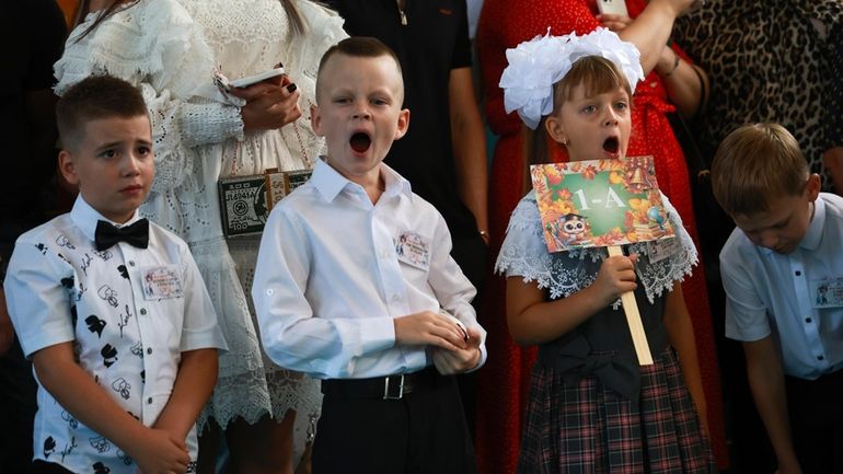 First graders yawn as they attend a ceremony marking the...