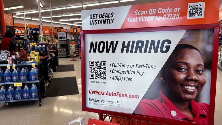 A hiring sign is displayed at a retail store in...