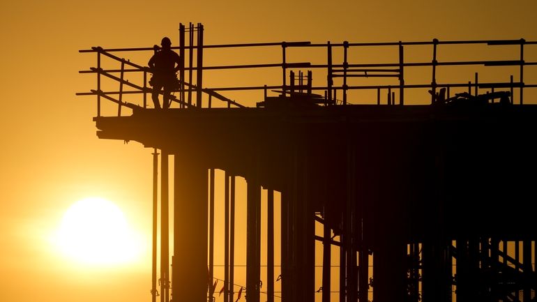 Construction workers start their day as the sun rises on...