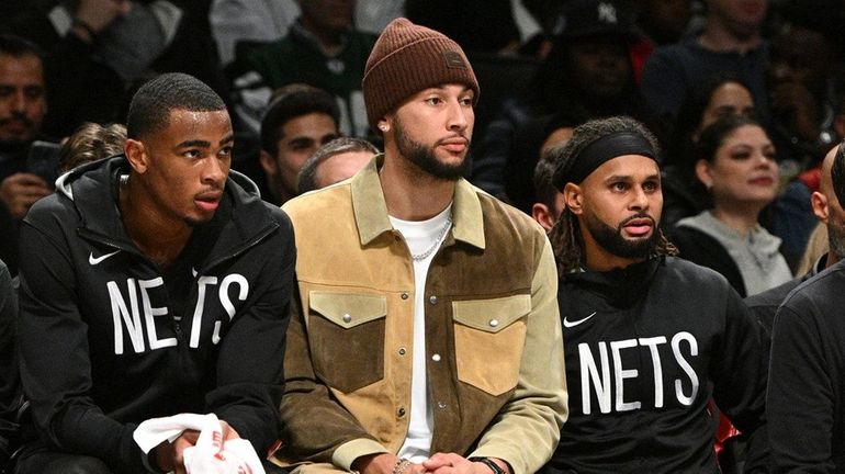 Brooklyn Nets guard Ben Simmons, center, sits on the bench...