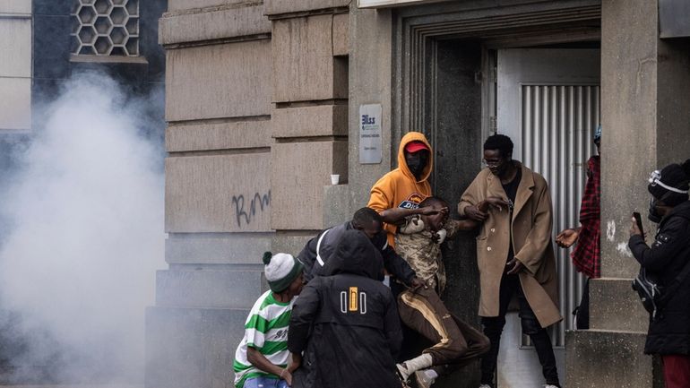 People help an injured man during a protest in Nairobi,...