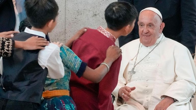 Pope Francis is welcomed by dancing children as he arrives...