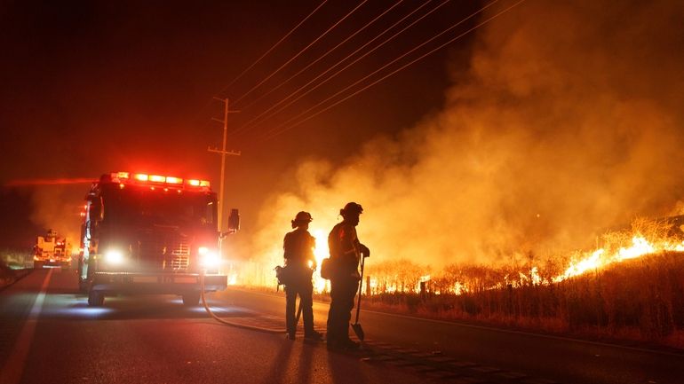 Firefighters monitor as flames consume brush along Gilman Springs Road...