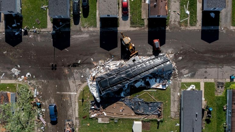 A storm damaged mobile home rests in the street at...