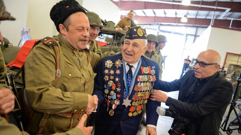 Leonid Rosenberg, of Brooklyn, greets reenactors during a ceremony to...