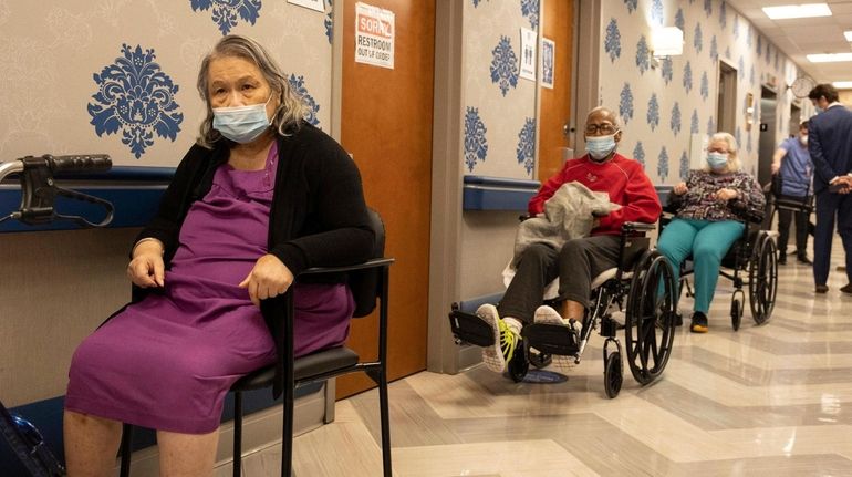 Nursing home residents wait on line to receive a COVID-19...