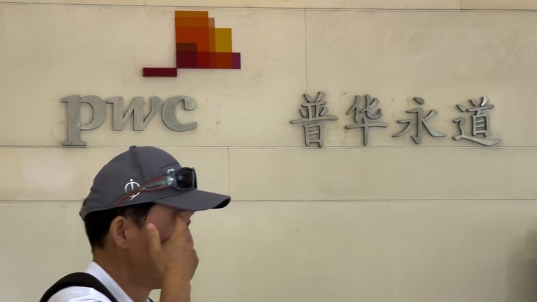 A man walks by the audit firm PricewaterhouseCoopers (PWC) office,...