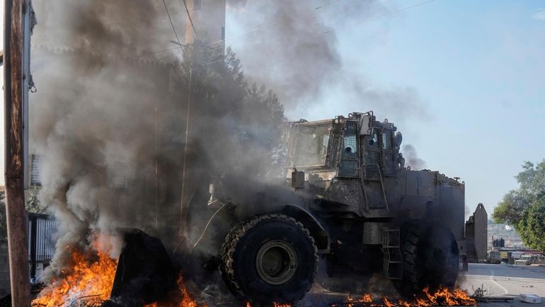 An Israeli army vehicle removes tires blocking roads that Palestinians...