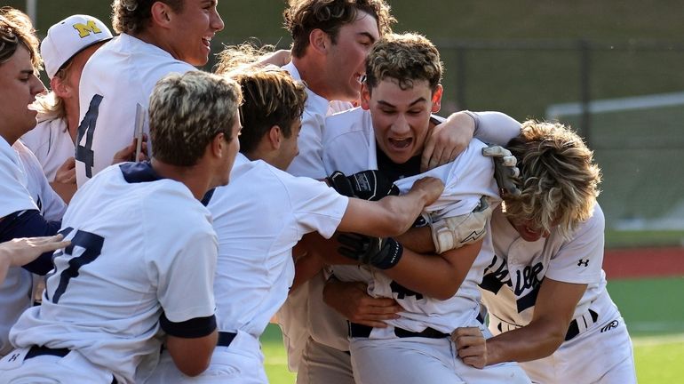 Massapequa's Erik Paulsen is mobbed by his teammates after hitting...