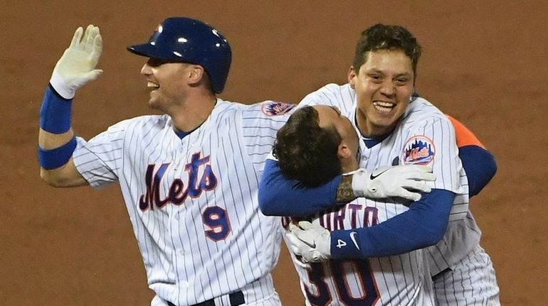 The Mets' Wilmer Flores celebrates his walk-off sacrifice fly with...