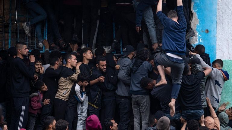 Palestinian crowds struggle to buy bread from a bakery in...