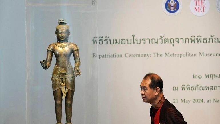 Thai person looks at a standing Shiva sculpture from the...