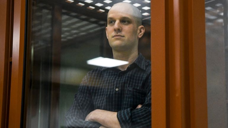 Wall Street Journal reporter Evan Gershkovich stands in a glass...