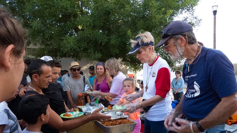 Volunteers with Team Brownsville serve food to people gathered at...