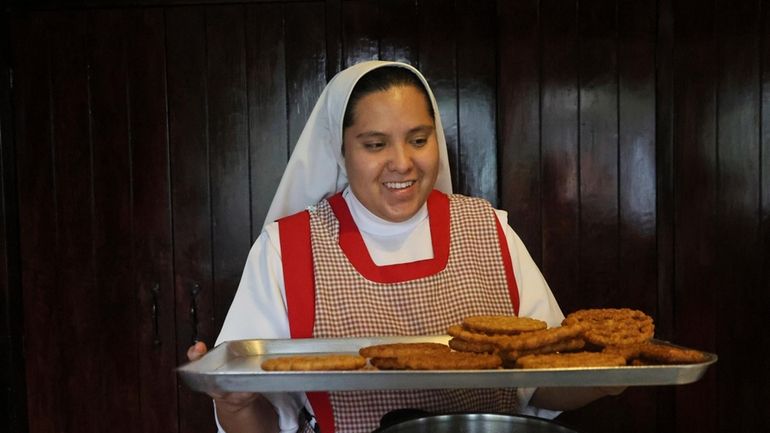 Nun Maria de Jesus Frayle, 24, holds a tray with...