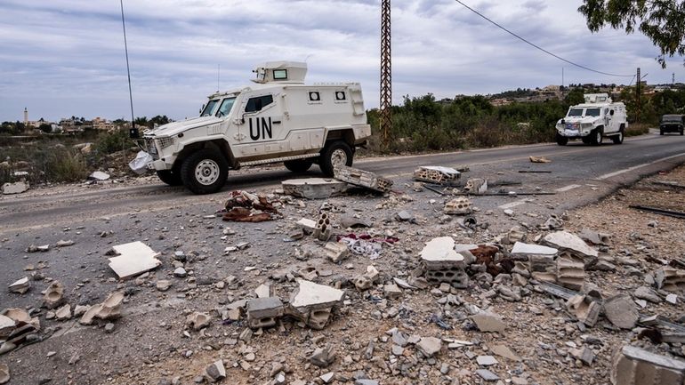 U.N. peacekeepers patrol next to a damage house in the...