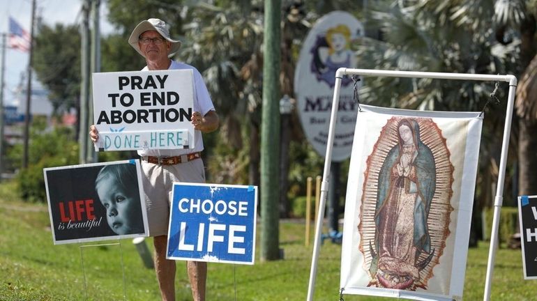 Dave Behrle, 70, of Safety Harbor holds a sign while...