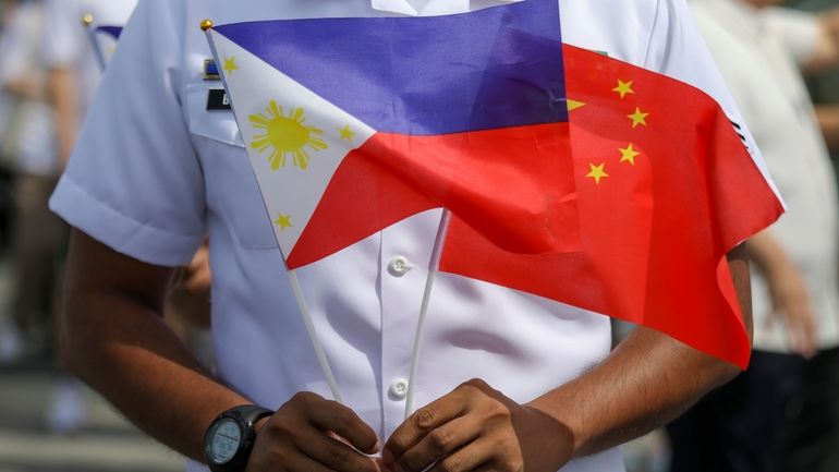 A member of the Philippine Coast Guard holds flags during...