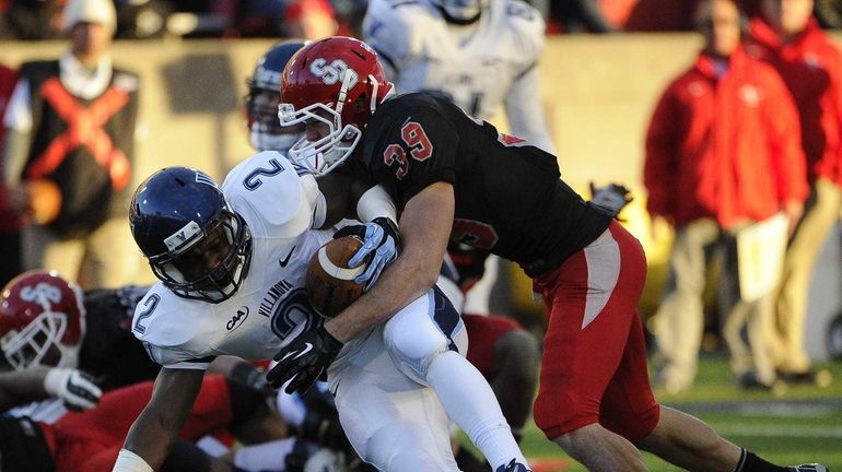 Stony Brook's Christian Ricard tackles Villanova's running back Kevin Monangai...