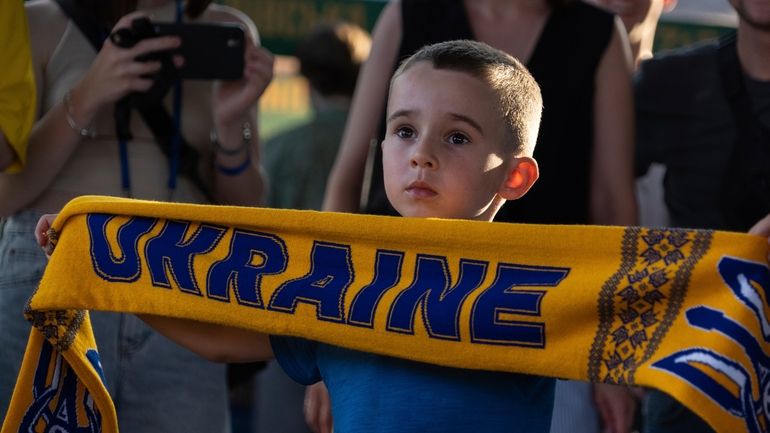 Mikhail, 5 holds a scarf with the inscription "Ukraine" during...