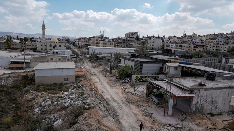 A man walks on a damaged road following an Israeli...