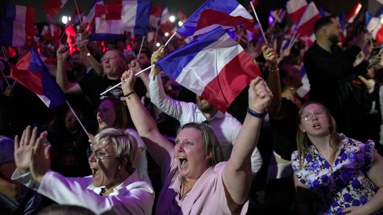 Supporters of French far right leader Marine Le Pen react...