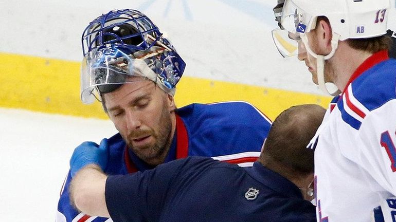 New York Rangers goalie Henrik Lundqvist is helped by a...