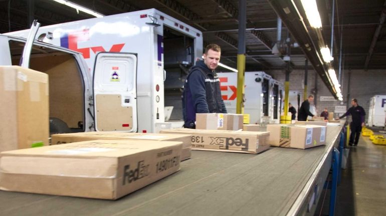 FedEx workers handle packages at the company facility in Melville...