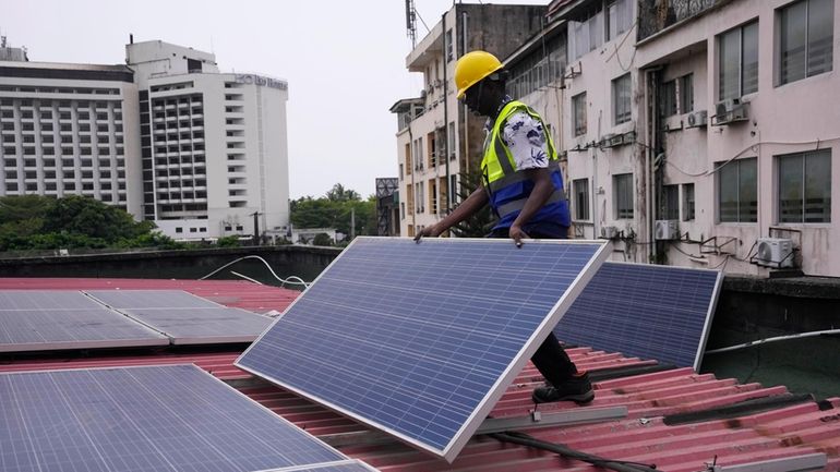 Oladapo Adekunle, an engineer with Rensource Energy, installs solar panels...