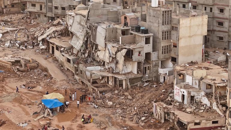 Rescuers and relatives of victims set up tents in front...