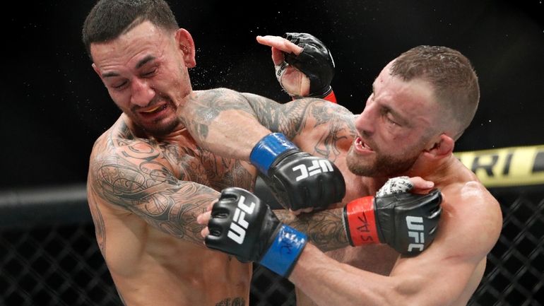 FILE - Alexander Volkanovski lands an elbow to Max Holloway...