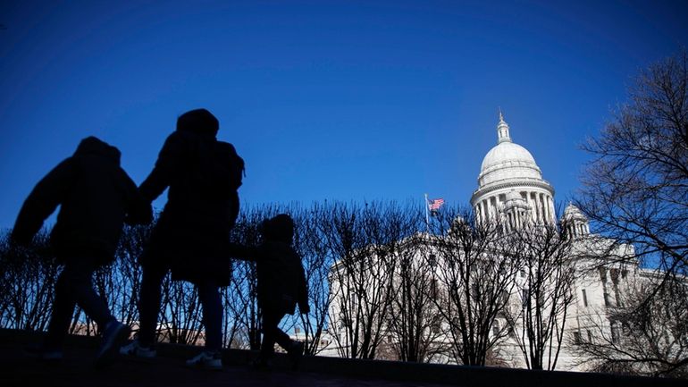 FILE — Pedestrians walk past the Rhode Island Statehouse, March...