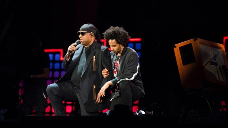 Stevie Wonder takes a knee "for America" with his son...