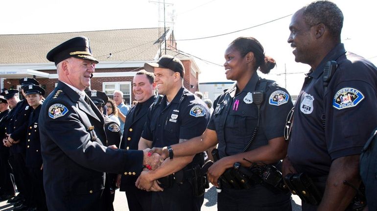 Hempstead Police Chief Michael McGowan shakes Officer S. Smith's hand...