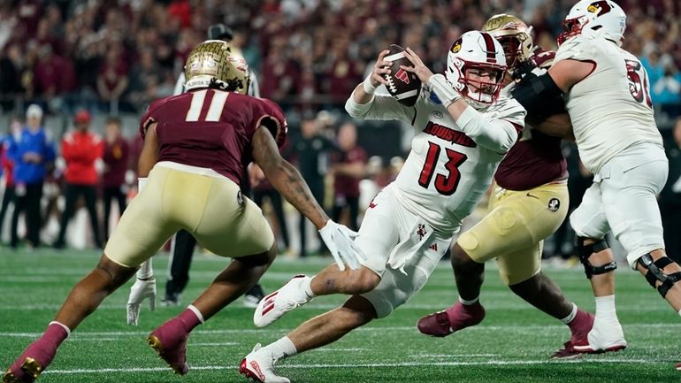 Louisville quarterback Jack Plummer tries to cut past Florida State...