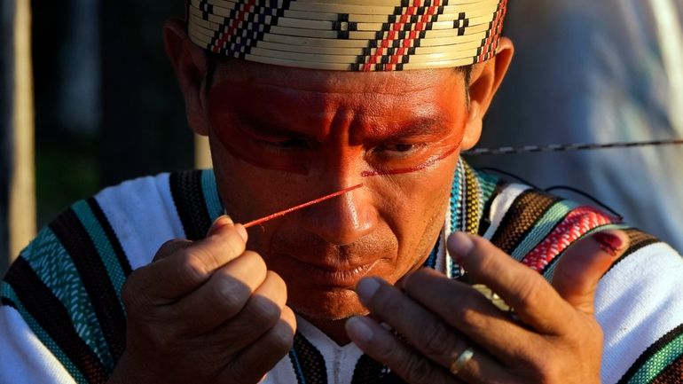 An Ashaninka Indigenous man applies face paint during the annual...