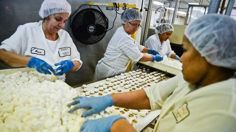 Employees process caramel chocolate candy inside the Nassau Candy factory...