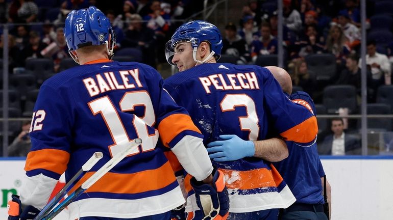 Adam Pelech #3 of the Islanders is helped off the ice...