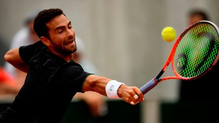 Noah Rubin plays a return to John Isner during their...