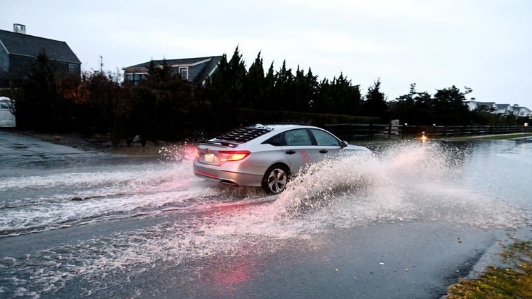 A car tries to naviage flooding on Dune Road in...