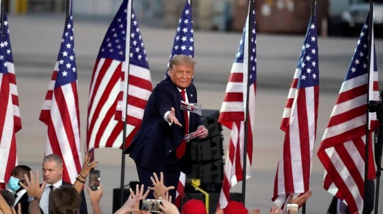 President Donald Trump tosses items to supporters as he arrives...