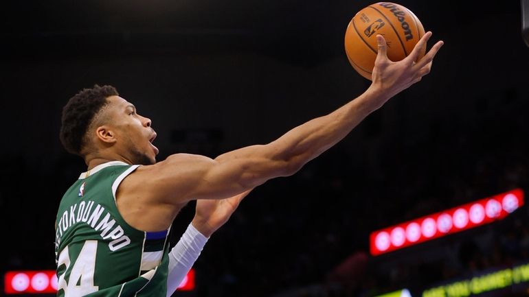 Milwaukee Bucks forward Giannis Antetokounmpo goes to the basket and...