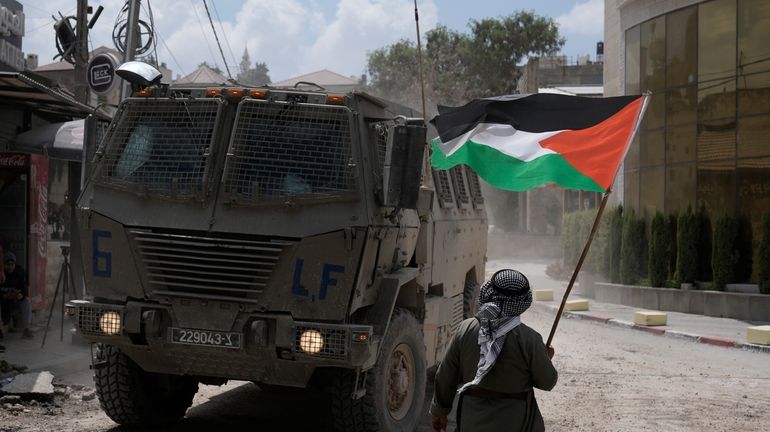 A man waves a Palestinian flag as an Israeli armoured...