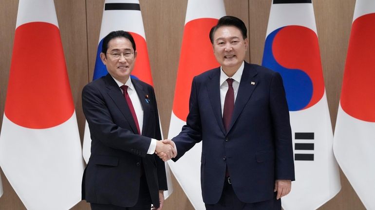 South Korean President Yoon Suk Yeol, right, shakes hands with...