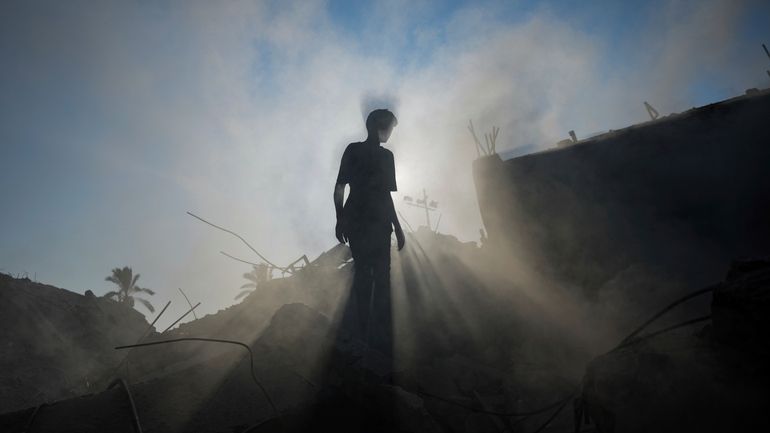 A Palestinian child inspects the rubble of a school destroyed...