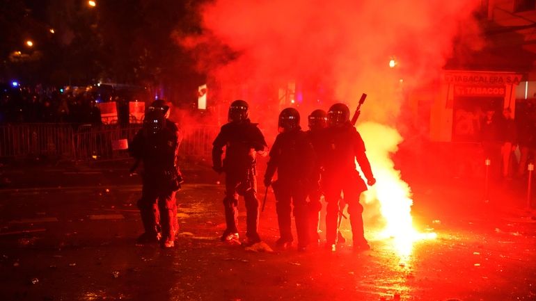 Riot police officers take position in a cloud of tear...