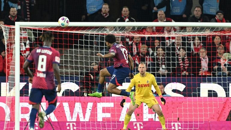 Leipzig's Lois Openda, center, scores during the Bundesliga soccer match...