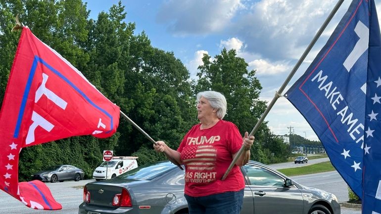 Suzanne Brown waves flags for Donald Trump before a ceremony...